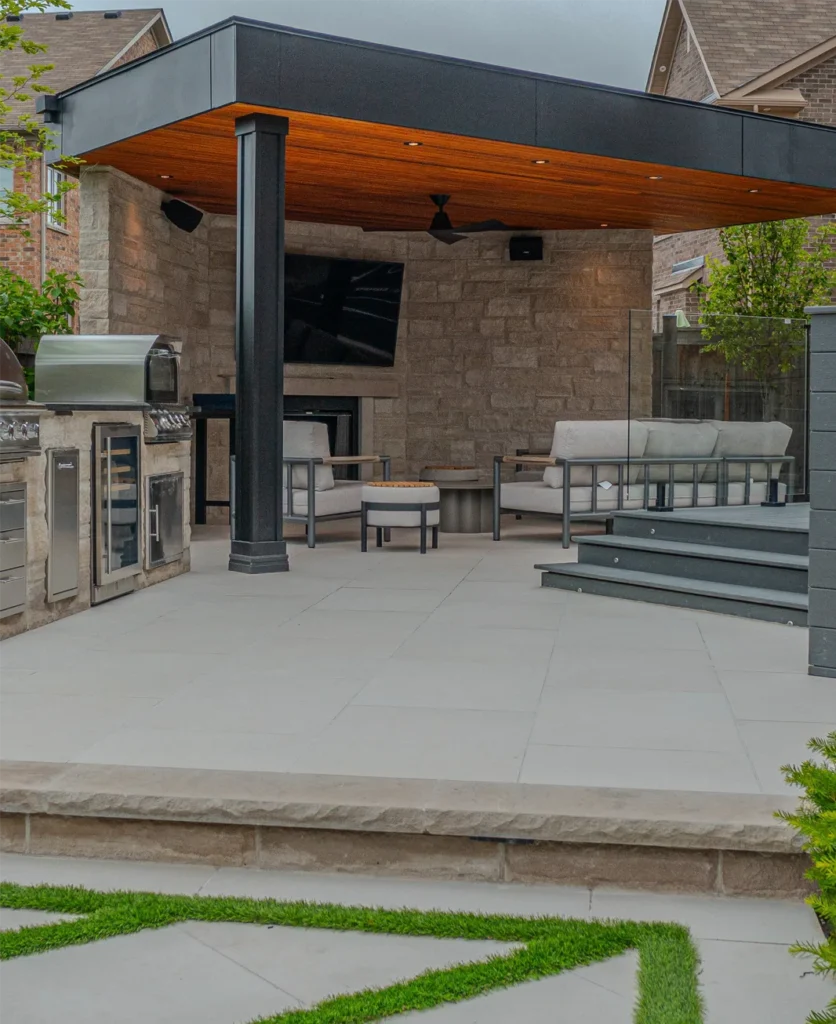 A backyard porcelain patio and a entertainment structure with a TV in it installed by Mutti Landscaping