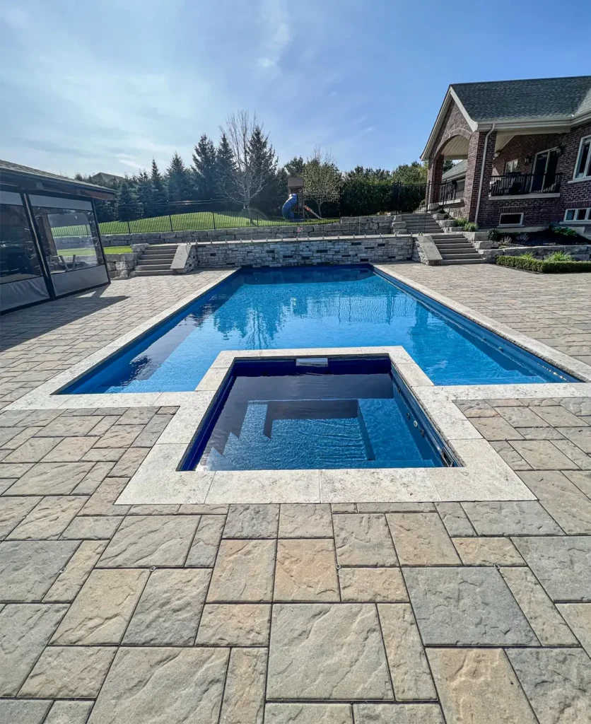 A backyard patio and walkway installation around a pool completed by Mutti Landscaping