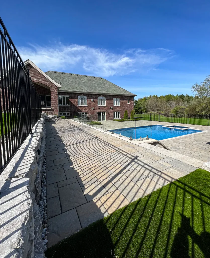 A backyard patio and walkway installation around a pool completed by Mutti Landscaping
