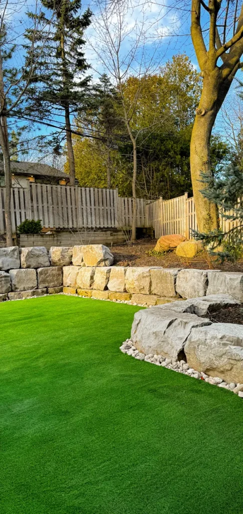 A backyard landscaping with several massive rocks completed by Mutti Landscaping
